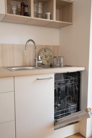 A kitchen with a built-in dishwasher, a stainless steel sink, and wooden cabinets. - Modern apartment in a quiet location. With an underground parking garage, ski storage, and bike storage. (Sankt Anton am Arlberg)