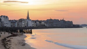 A coastal cityscape with a prominent church spire, waterfront promenade, and buildings along the shore.