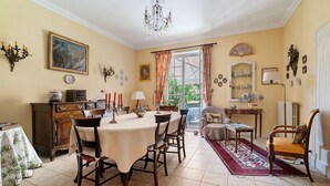 A dining room with a table set for four, a chandelier, and a view through a glass door.
