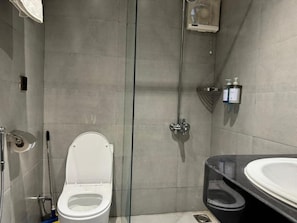 Ein modernes Badezimmer mit einer Duschkabine aus Glas, einer weißen Toilette und einem schwarzen Waschbecken.