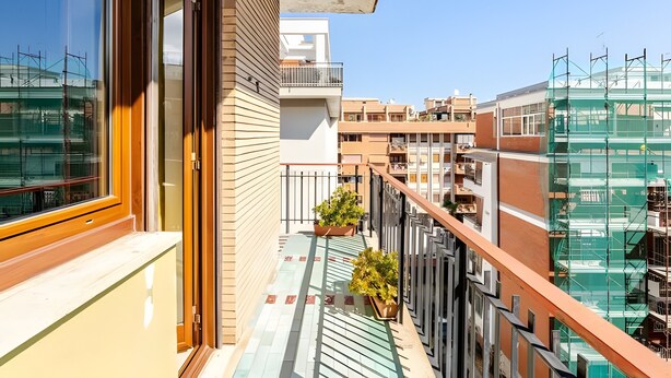 Un appartement moderne doté d ’un balcon, de grandes fenêtres et offrant une vue sur les immeubles voisins.