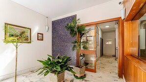 Un couloir agrémenté de plantes en pot, un mur recouvert de carreaux et un banc en bois.