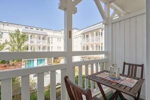 A balcony with a table and chairs, overlooking a pool and buildings. - Studio mit Balkon im Seepark Sellin (Sellin)