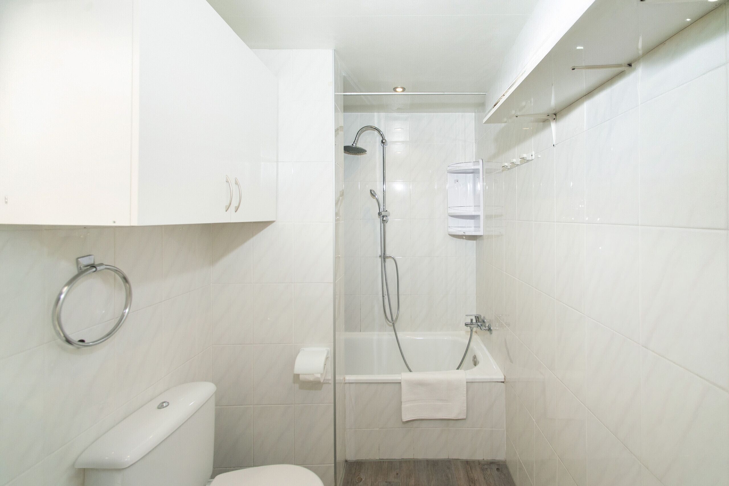 A bathroom with a toilet, a shower, a bathtub, and a towel rack.