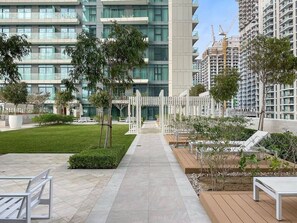 A modern residential building with a central pathway, outdoor seating, and greenery. - FIRST CLASS |1BR| Sea Views | Direct Beach Access (Dubai Harbour)