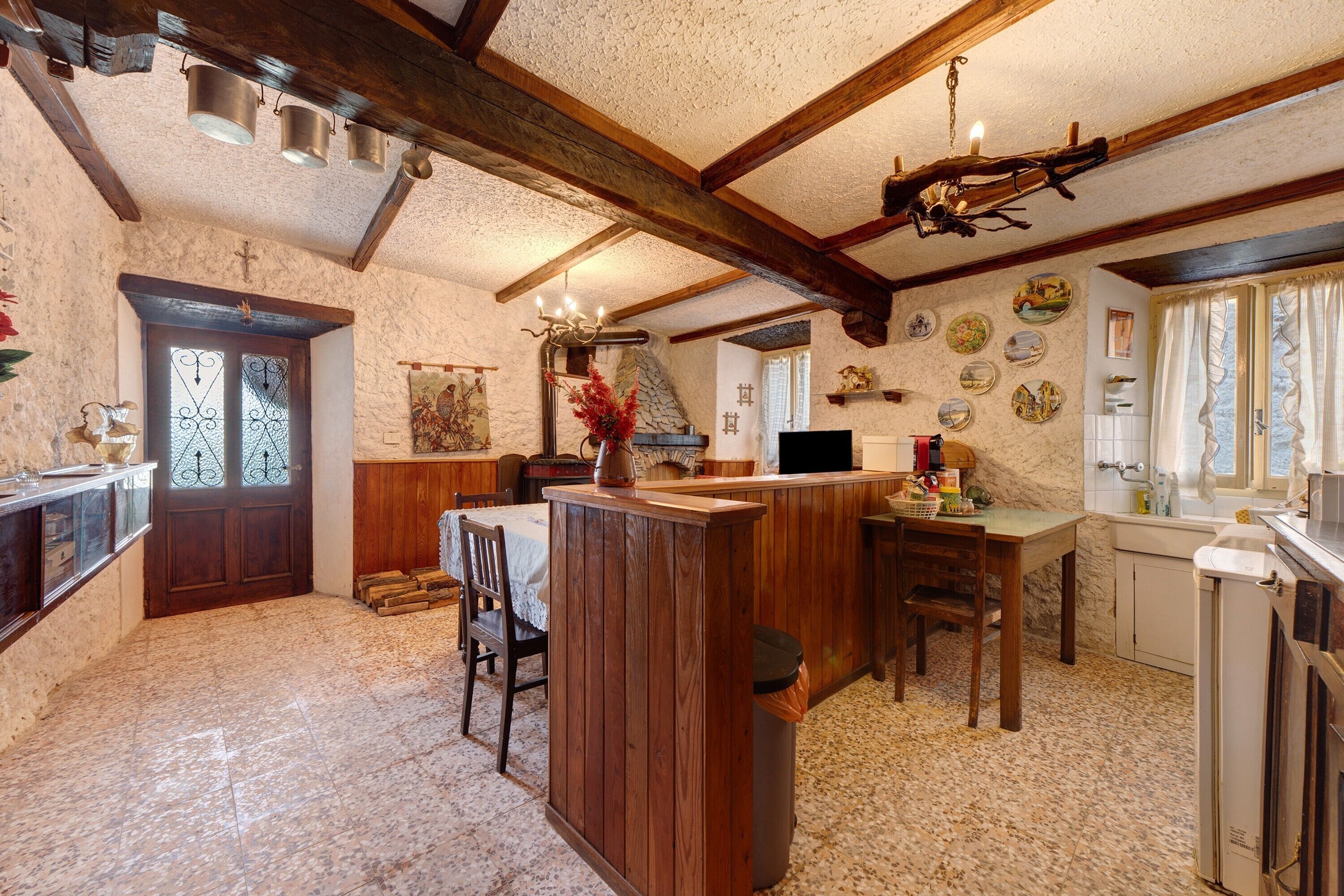 Une cuisine rustique avec des poutres en bois, un mur en pierre et un sol carrelé.