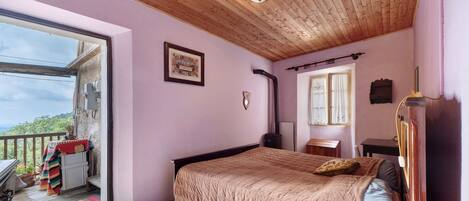 Un dormitorio con cama, ventana, puerta y vistas al exterior.