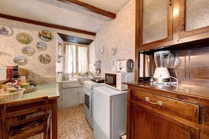 A compact kitchen with a washing machine, a microwave, and a blender on the counter.