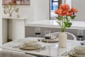 A dining table set with plates, bowls, and wine glasses, accompanied by a vase of flowers. - FIRST CLASS | 2BR | Luxury Escape in Meydan (Meydan)