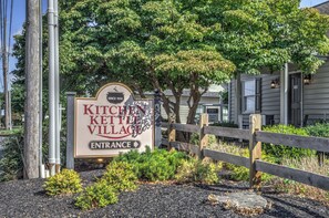 A sign for 'KITCHEN KETTLE VILLAGE' with an entrance arrow, surrounded by trees and a wooden fence. - 2-bedroom apartment in gorgeous Ronks with cool AC (Ronks)