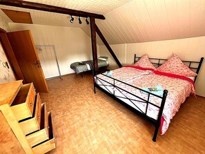 A bedroom with a bed, wooden furniture, and a sloped ceiling.