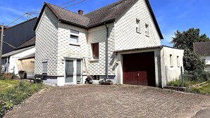 Et toetagers hus med garage, lille veranda og asfalteret indkørsel.