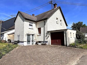 A two-story house with a garage, a small porch, and a paved driveway. - Holiday Home in Badem (Badem)
