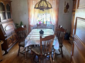 A dining area with a table set for four, surrounded by wooden chairs, a chandelier, and a cabinet with glass doors. - Holiday Home in Badem (Badem)