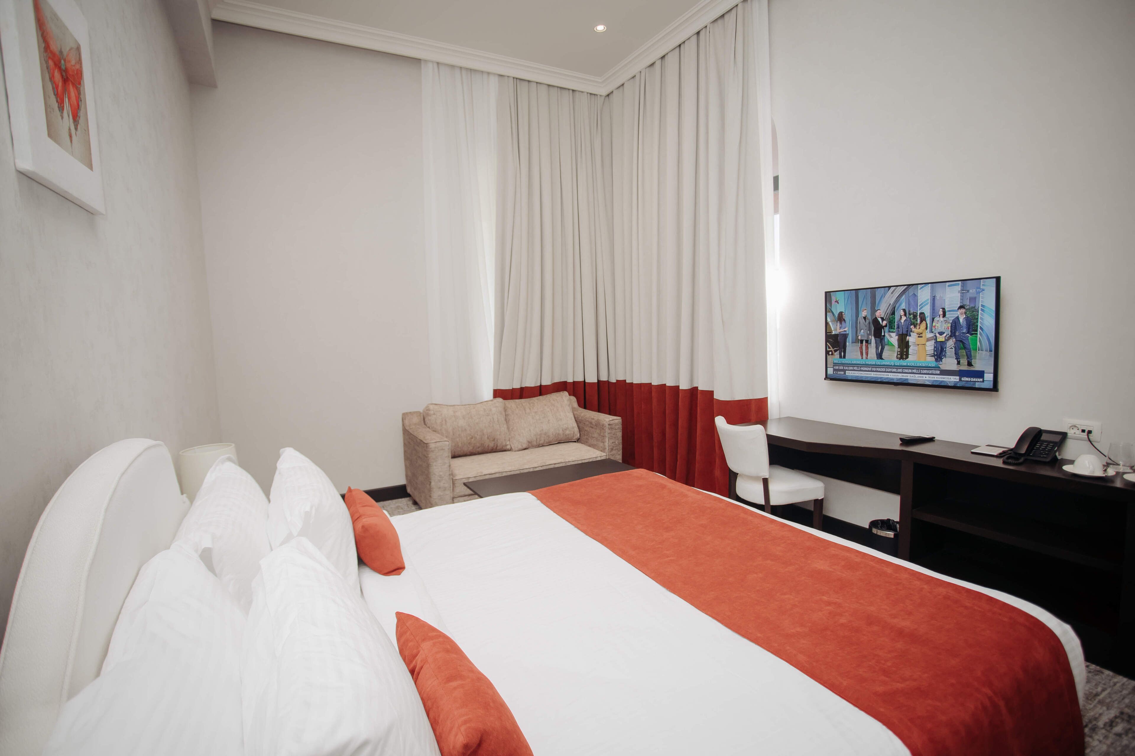 Habitación de hotel con cama, escritorio, silla, sofá y un cuadro en la pared.