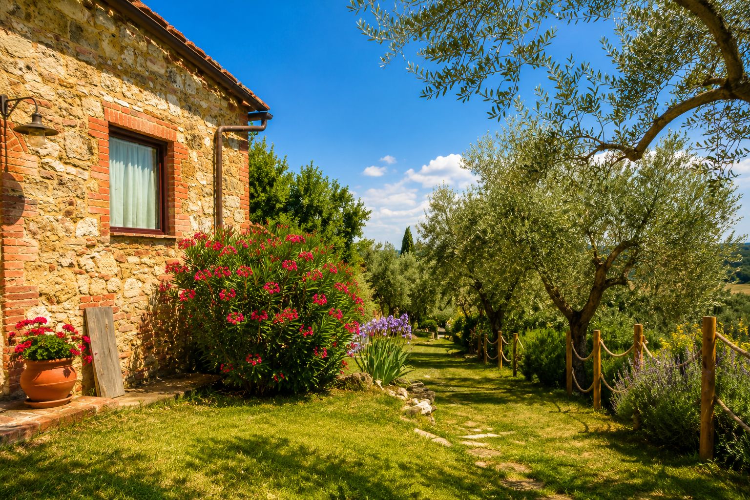 Un bâtiment en pierre avec une fenêtre, un jardin où poussent différentes plantes et un ciel bleu clair.