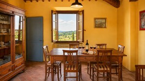 A dining area with a table set for six, a wine bottle, and glasses on the table. - Stunning "La Quercia" Apartment in a Country House with a Pool and Panoramic View (Toscana)