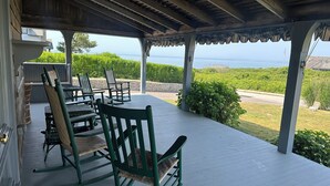 A covered outdoor seating area with wooden furniture and a view of the ocean. - Location, Location, Location! (Westerly)