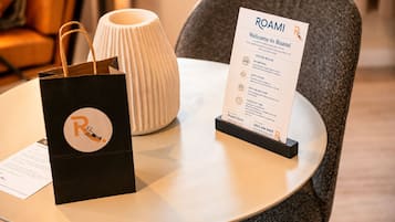 A Roami guest bag, a Roami welcome sign, and a white vase on a table.
