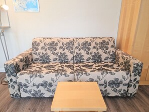 A sofa with a floral pattern, a wooden coffee table, and a map on the wall. - Ferienwohnung fur Zwei in Sellin mit Balkon und Wlan (Sellin)