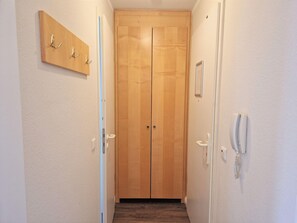Ein Flur mit Holztür, Kleiderhaken und Telefon.