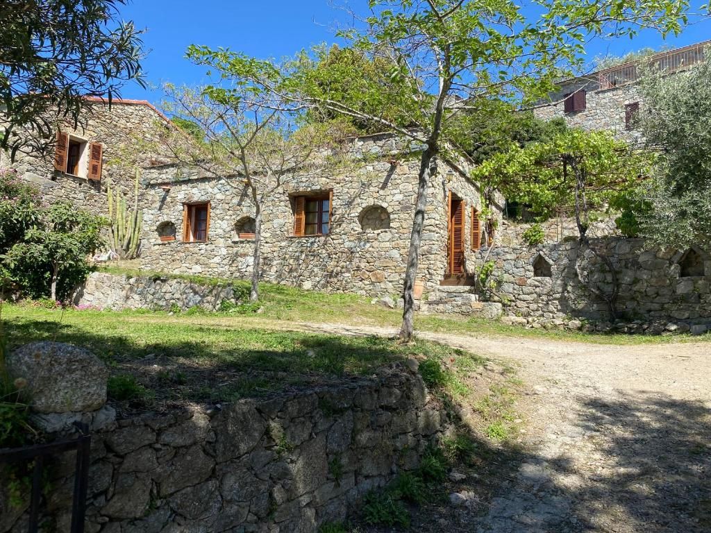 Un bâtiment en pierre doté de nombreuses fenêtres, avec un chemin de terre menant à l’entrée.