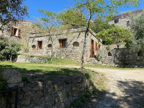 Um edifício de pedra com várias janelas e um caminho de terra que leva até ele.