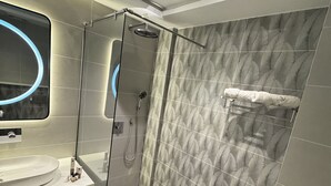 A modern bathroom with a glass-enclosed shower, a white sink, and a patterned wall.