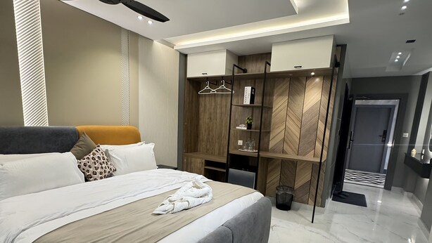A modern bedroom with a large bed, a ceiling fan, built-in wardrobe, and a marble floor.