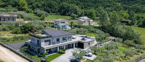 Una casa moderna de dos pisos con techo plano, paneles solares y un porche cubierto.