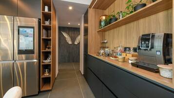 Een moderne keuken met een ingebouwde koffieapparaat, een koelkast en houten planken met planten.
