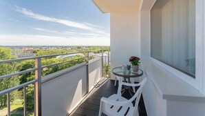 Un balcón con una mesa, sillas, una maceta y vistas de la ciudad.