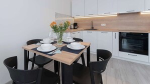 Una cocina moderna con armarios blancos, encimera de madera y cuatro sillas negras alrededor de una mesa de comedor.