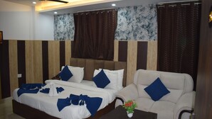 A hotel room with a bed, a sofa, a small table with a vase, and a ceiling fan.