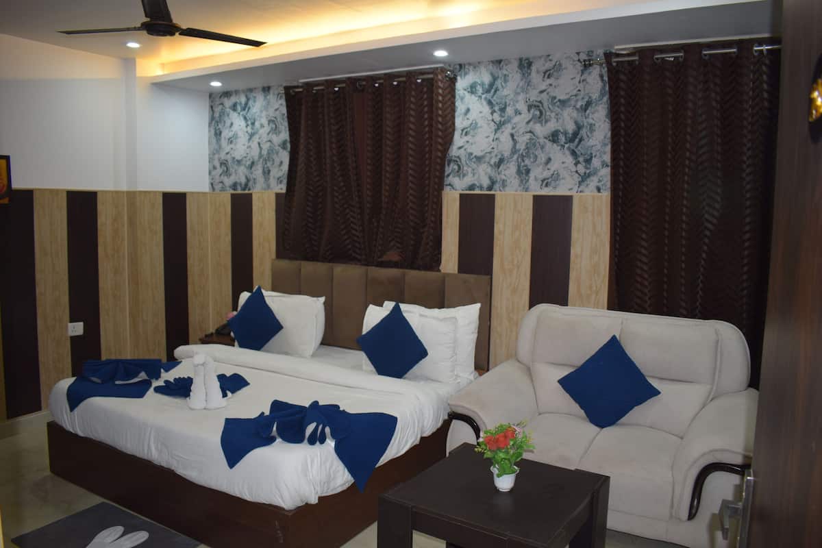 A hotel room with a bed, a sofa, a small table with a vase, and a ceiling fan.