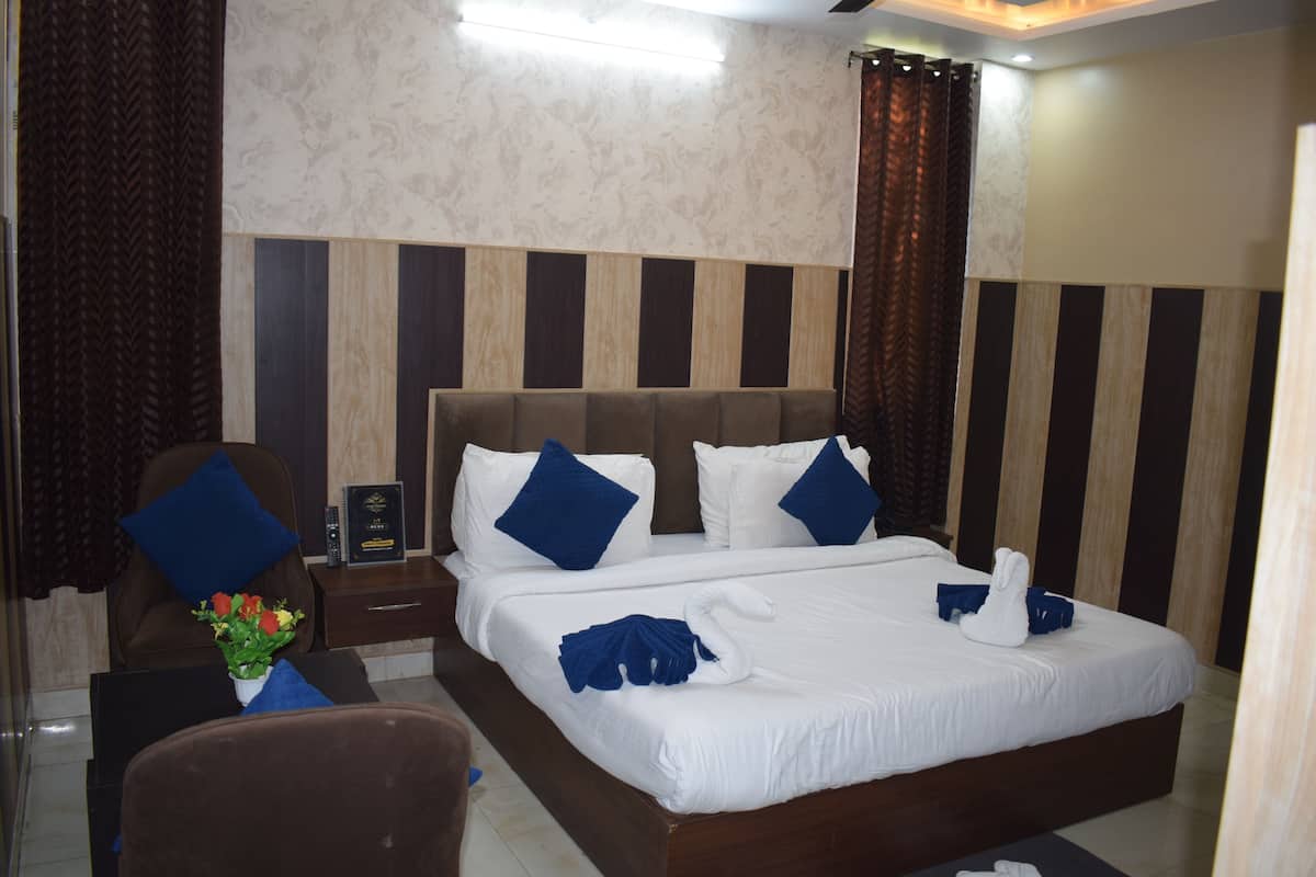 A hotel room with a large bed, a nightstand, a chair, and a desk.
