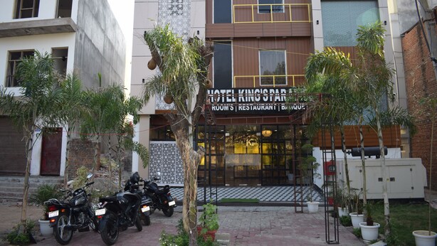 A hotel with a modern facade, a sign indicating it offers rooms, a restaurant, and a bar. Motorcycles are parked in front.