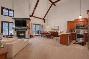 A spacious living room with a fireplace, a dining area, and a kitchen with modern appliances. - Tremblant Prestige - Manoir 112-10 (Mont-Tremblant)