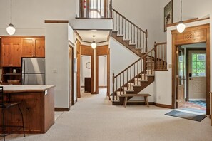 A spacious kitchen with wooden cabinets, a stainless steel refrigerator, and a bar area. - Tremblant Prestige - Manoir 112-10 (Mont-Tremblant)