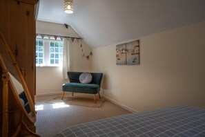 A bedroom with a bed, a window, a green sofa, a painting, and a staircase. - Finest Retreats | House on The Green (Derby)