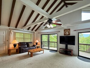 Ein Wohnzimmer mit Deckenventilator, Fernseher, Sofa und Couchtisch.