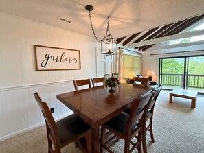 A dining room with a wooden table, chairs, a chandelier, and a 'gather' sign on the wall. - six-bedroom, four-bathroom home comfortably accommodates up to 17 guests (Sugar Mountain)