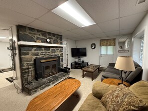 Una sala de estar con chimenea de piedra, televisor de pantalla plana, sofá, mesa de centro y lámpara.