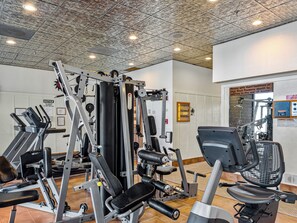 Ein Fitnessstudio mit verschiedenen Trainingsgeräten, einem Wandzeichen und einer Tür mit einem Warnschild.