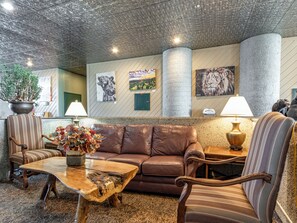 A lobby with a brown leather sofa, striped chairs, a wooden coffee table, and a potted plant. - Escape to the cool mountain air and breathtaking views (Sugar Mountain)