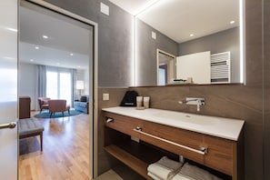 A modern bathroom with a large mirror, wooden vanity, and a glass door leading to a living area. - Casa Palma (Muralto)