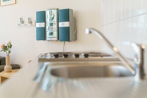 A kitchen with a gas stove, a sink, and a wall-mounted appliance unit. - Attraktive Ferienwohnung fur Zwei im Seepark Sellin (Sellin)