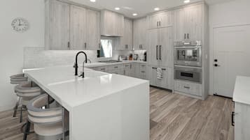 A modern kitchen with a large island, bar stools, and built-in appliances.