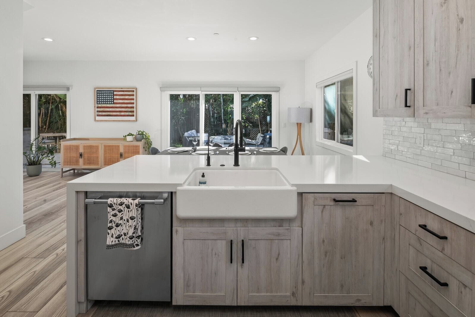 A modern kitchen with a large island, white cabinetry, and a view of the outdoors.
