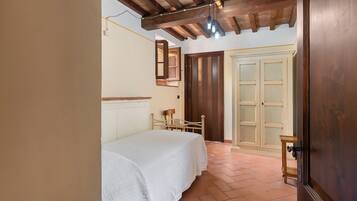 Una camera da letto con un letto, travi in legno al soffitto, un armadio e una porta.